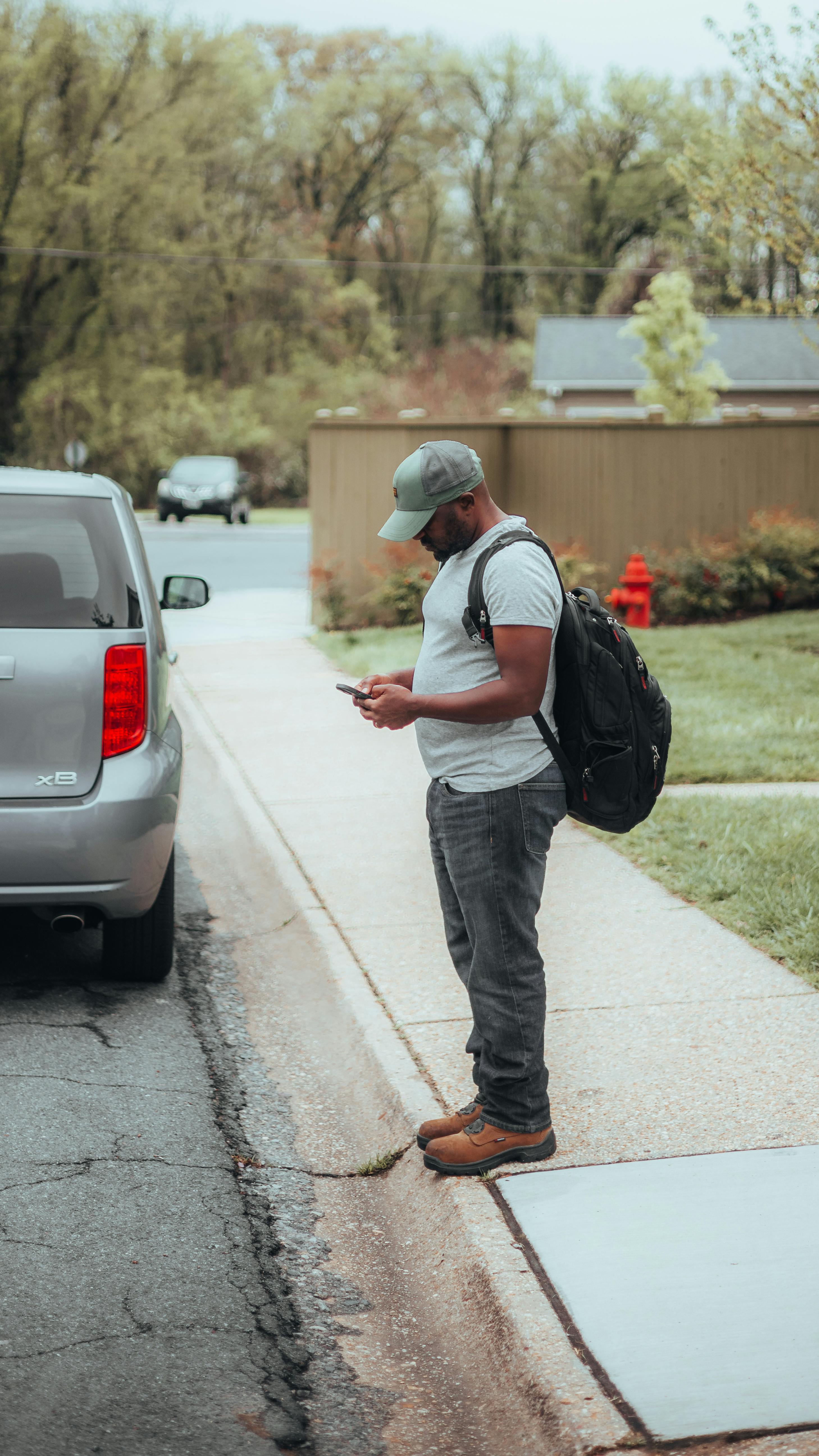 Homme avec un telephone en main devant sa voiture
